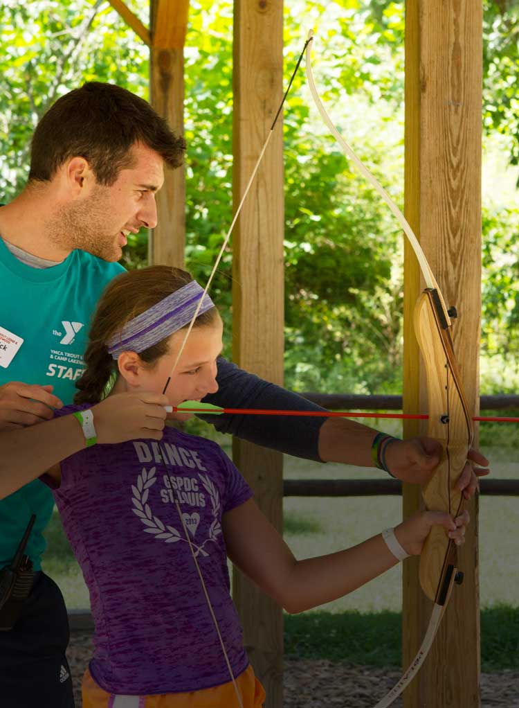 Camp counselor and camper practicing archery together